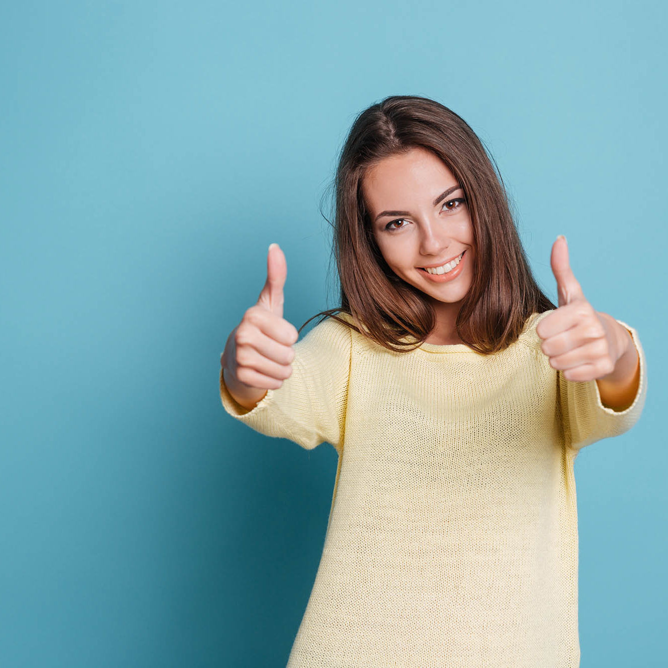 Beautiful woman giving thumbs up over blue background